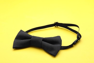 Photo of Stylish black bow tie on yellow background