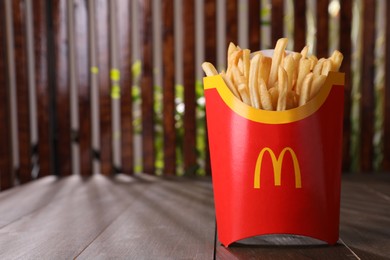 Photo of MYKOLAIV, UKRAINE - AUGUST 12, 2021: Big portion of McDonald's French fries on wooden table. Space for text