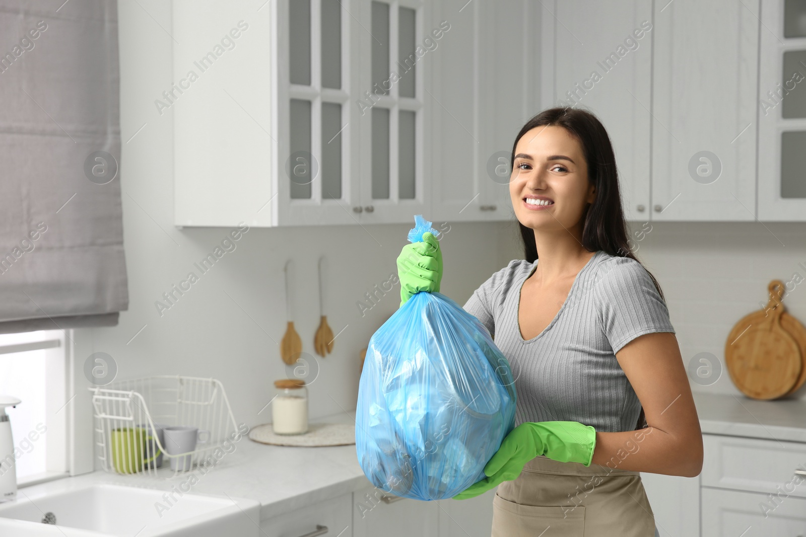 Photo of Woman holding full garbage bag at home