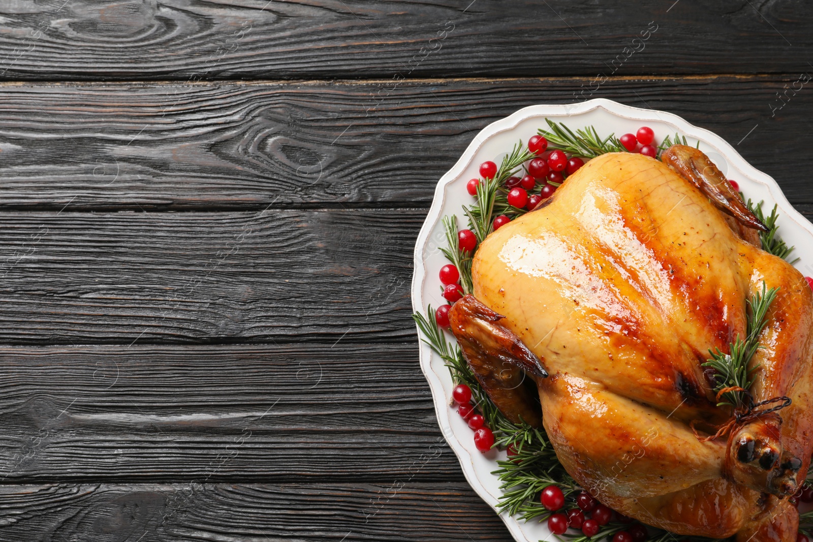 Photo of Platter of cooked turkey with garnish on wooden background, top view. Space for text