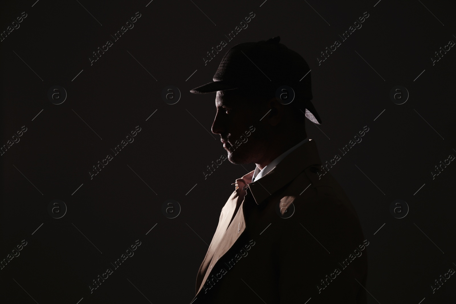 Photo of Old fashioned detective in hat on dark background. Space for text