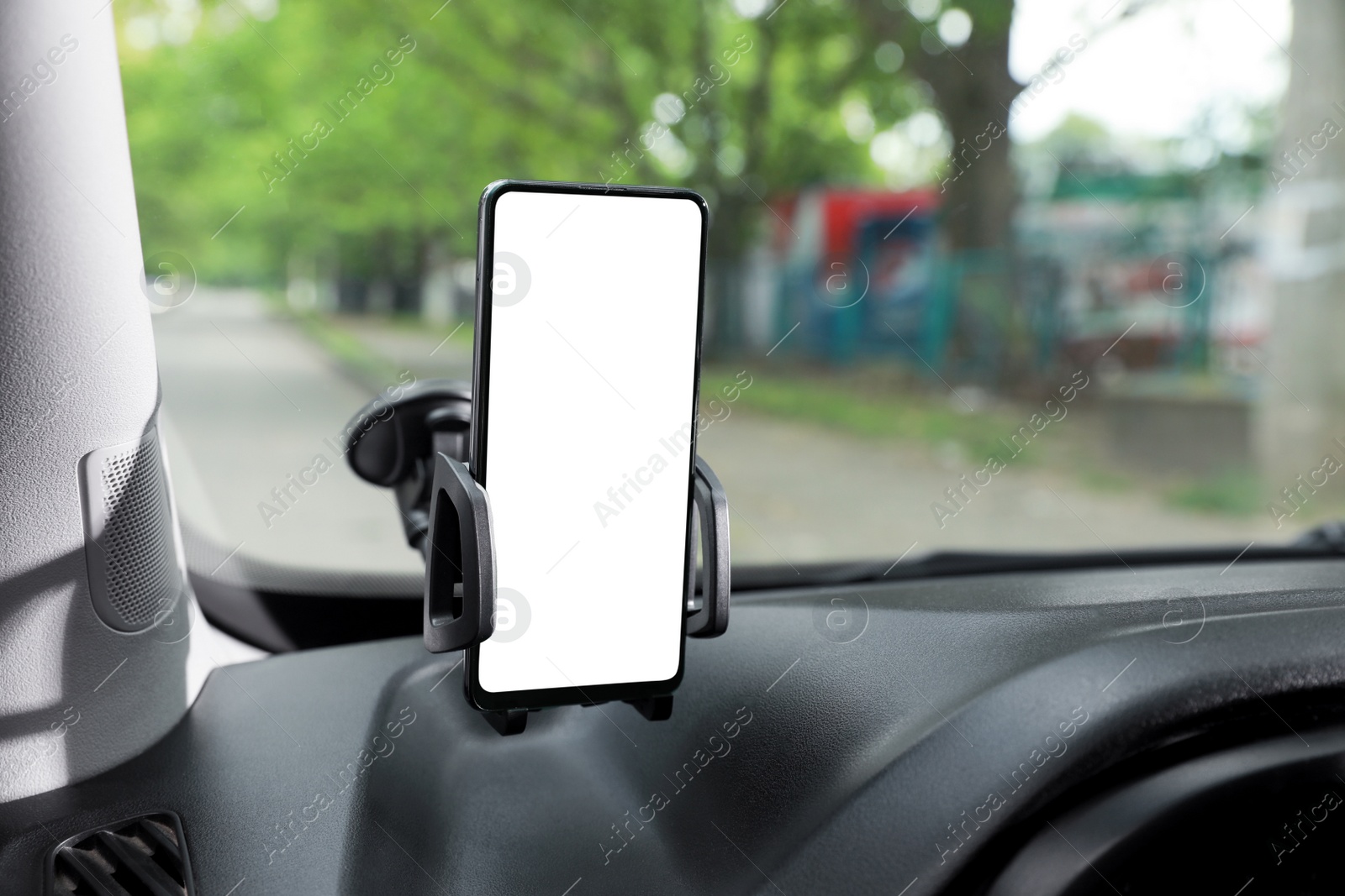 Photo of Car holder with modern mobile phone on windshield of automobile. Mockup for design