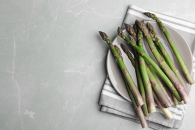 Photo of Fresh raw asparagus on light grey marble table, flat lay. Space for text