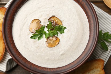 Fresh homemade mushroom soup in ceramic bowl on wooden table, top view