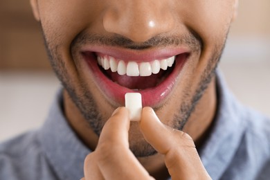 Man with chewing gum on blurred background, closeup