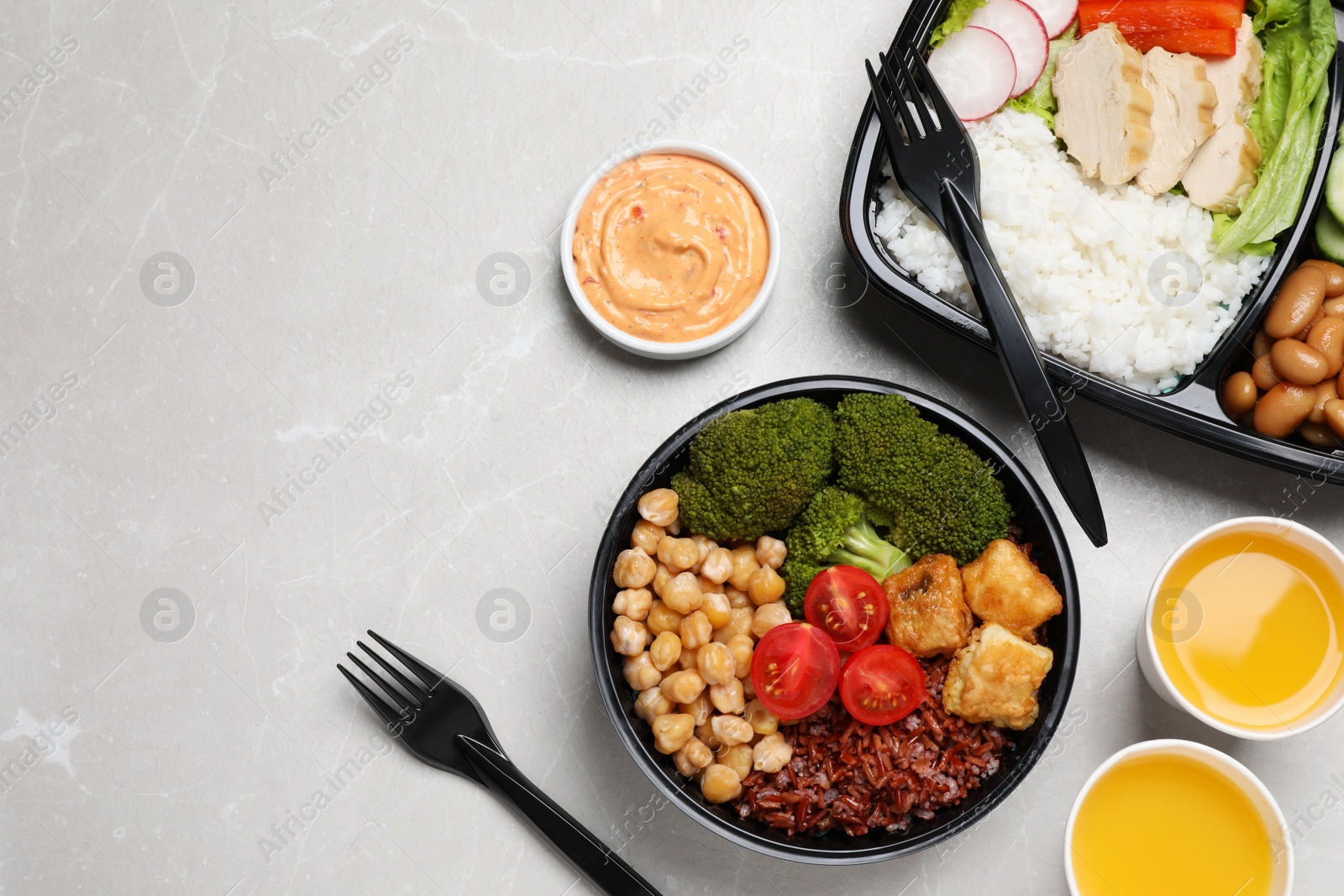 Photo of Healthy takeaway meals served with sauce and juice on light grey marble table, flat lay. Space for text