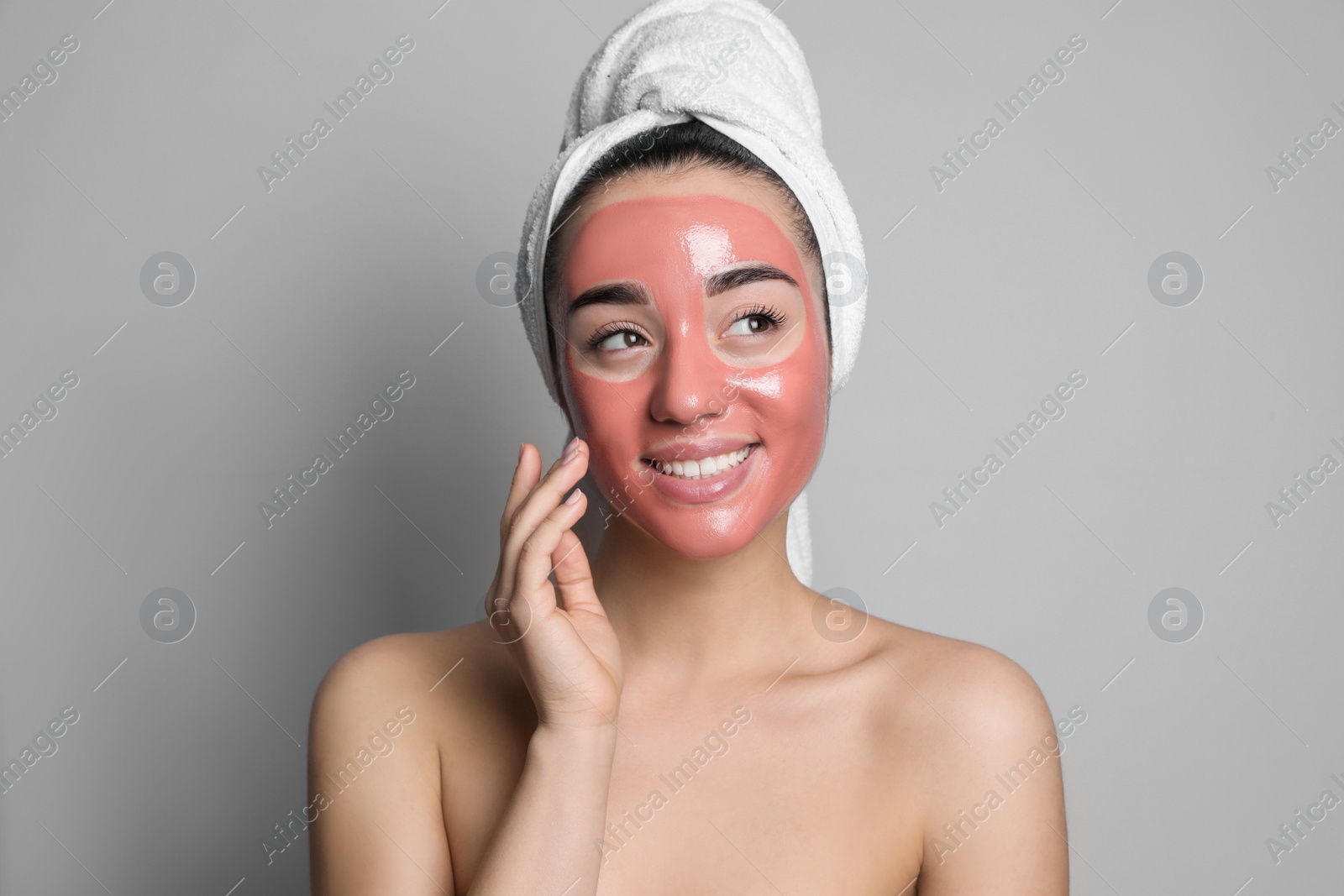 Photo of Woman applying pomegranate face mask on grey background