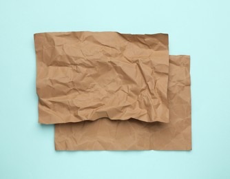 Photo of Sheets of crumpled brown paper on light blue background, top view