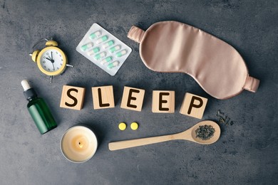 Photo of Flat lay composition with word Sleep made of wooden cubes and insomnia remedies on grey background