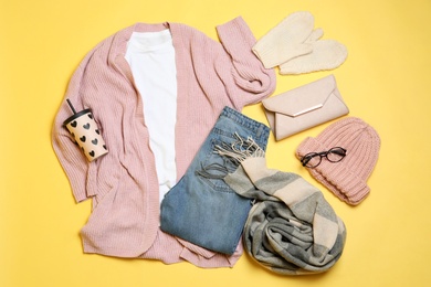 Flat lay composition with winter clothes and glasses on yellow background