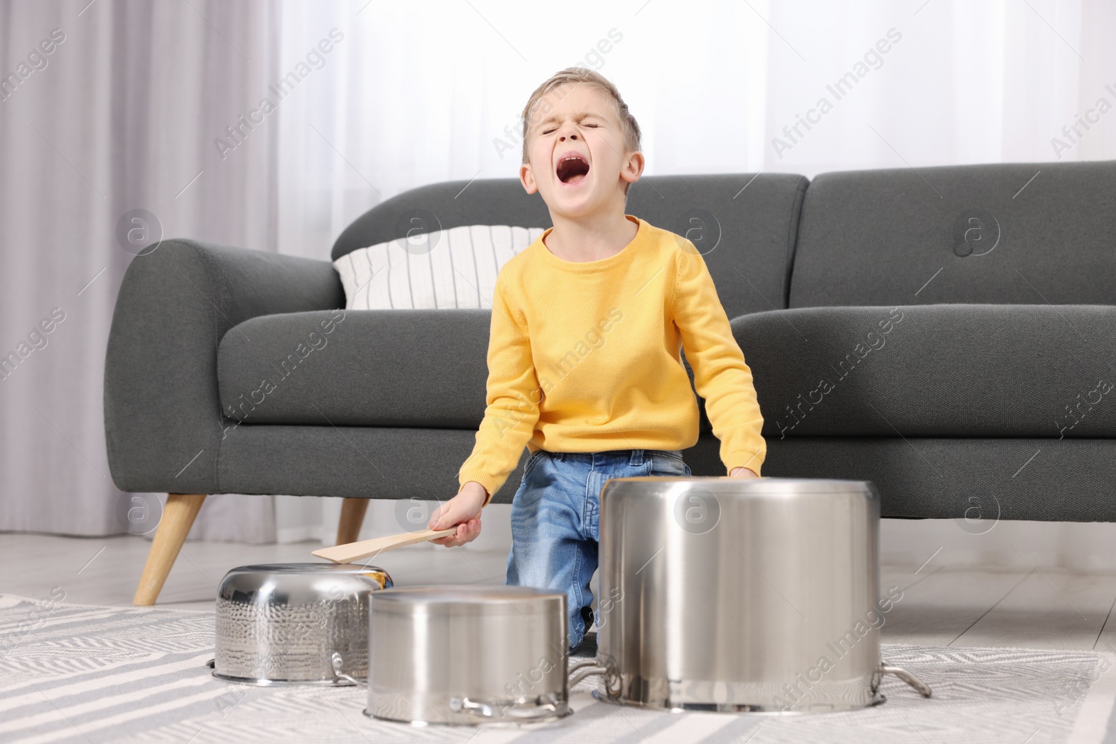 Photo of Little boy pretending to play drums on pots at home