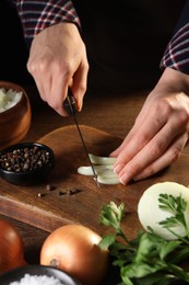 Photo of Woman cutting ripe onion at wooden table, closeup