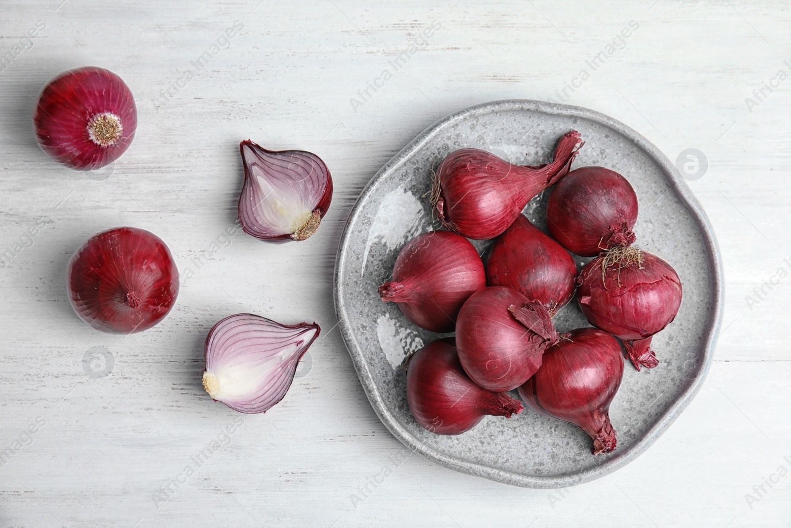 Photo of Plate with ripe red onions on table, top view