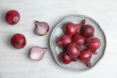 Plate with ripe red onions on table, top view