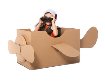 Cute little boy playing with binoculars and cardboard airplane on white background