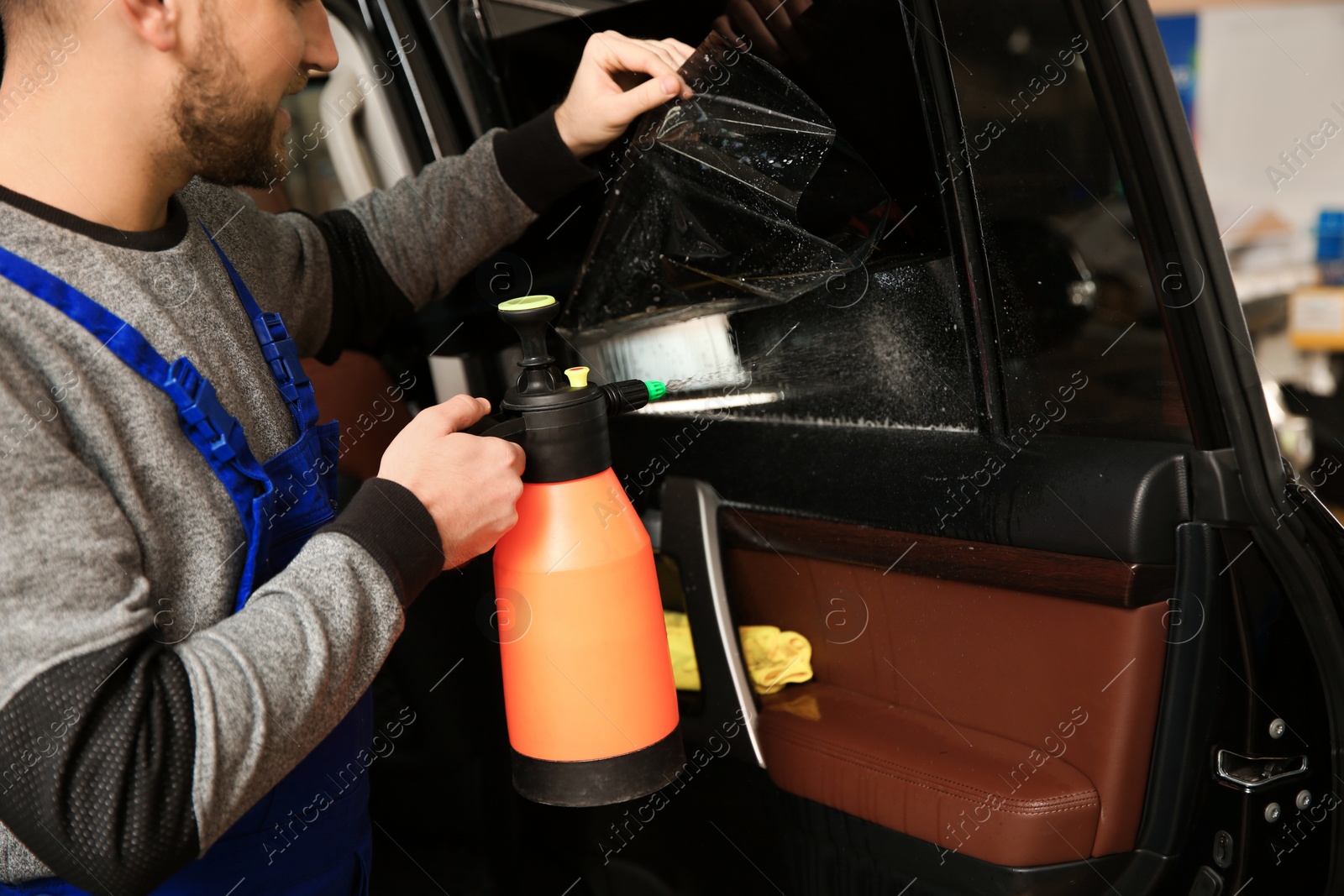 Photo of Skilled worker tinting car window in shop