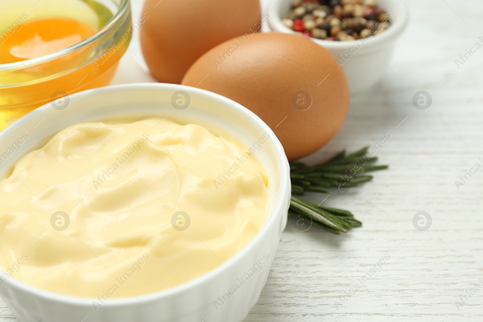 Photo of Delicious homemade mayonnaise with ingredients on white wooden table, closeup. Space for text