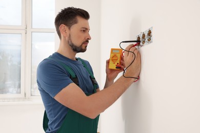 Photo of Electrician in uniform with tester checking voltage indoors