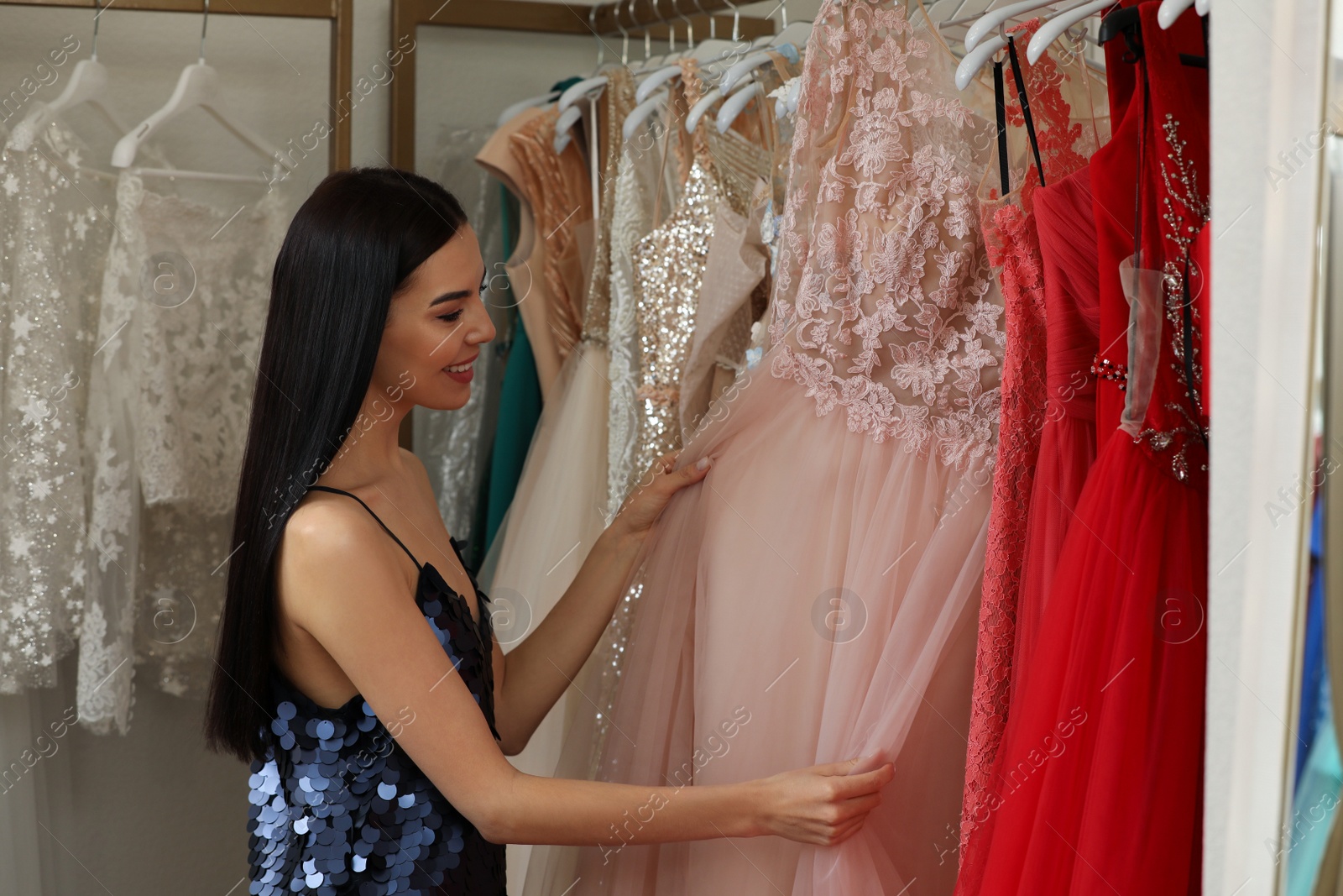 Photo of Woman choosing dress in rental clothing salon