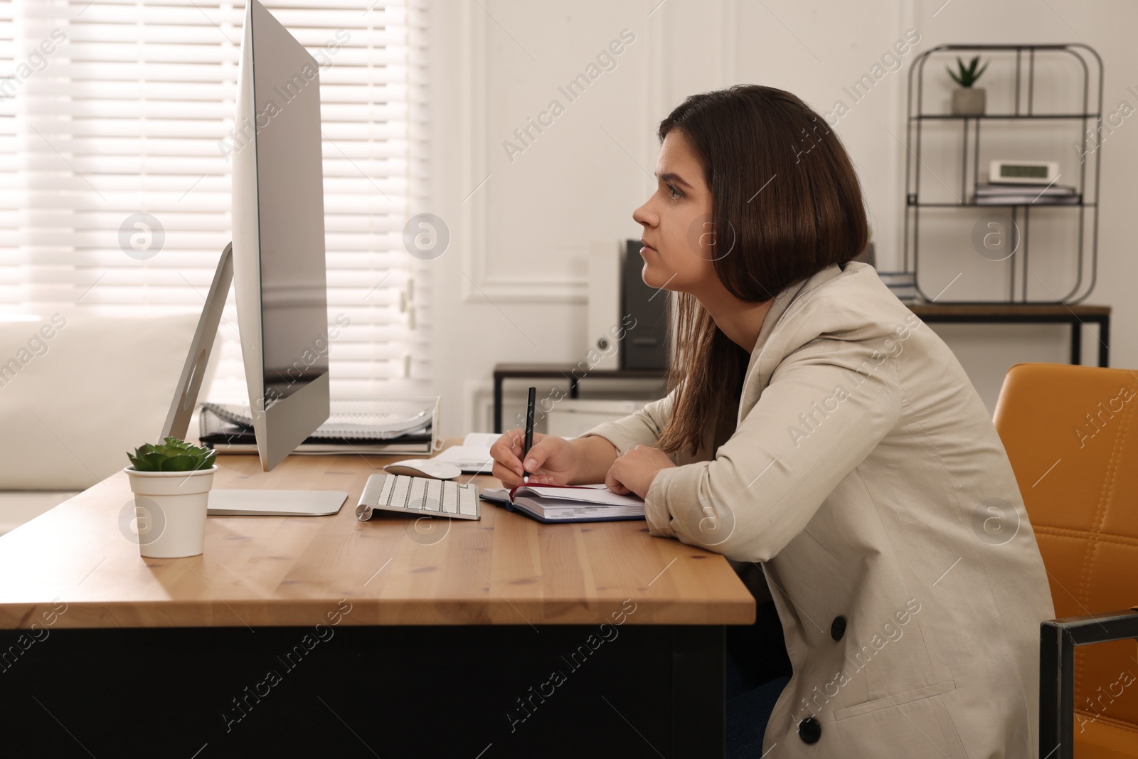 Photo of Young woman with bad posture working on computer in office