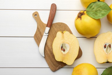 Photo of Tasty ripe quince fruits and knife on white wooden table, flat lay. Space for text