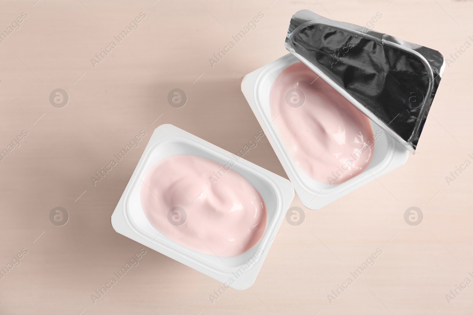 Photo of Plastic cups with yummy yogurt on wooden table