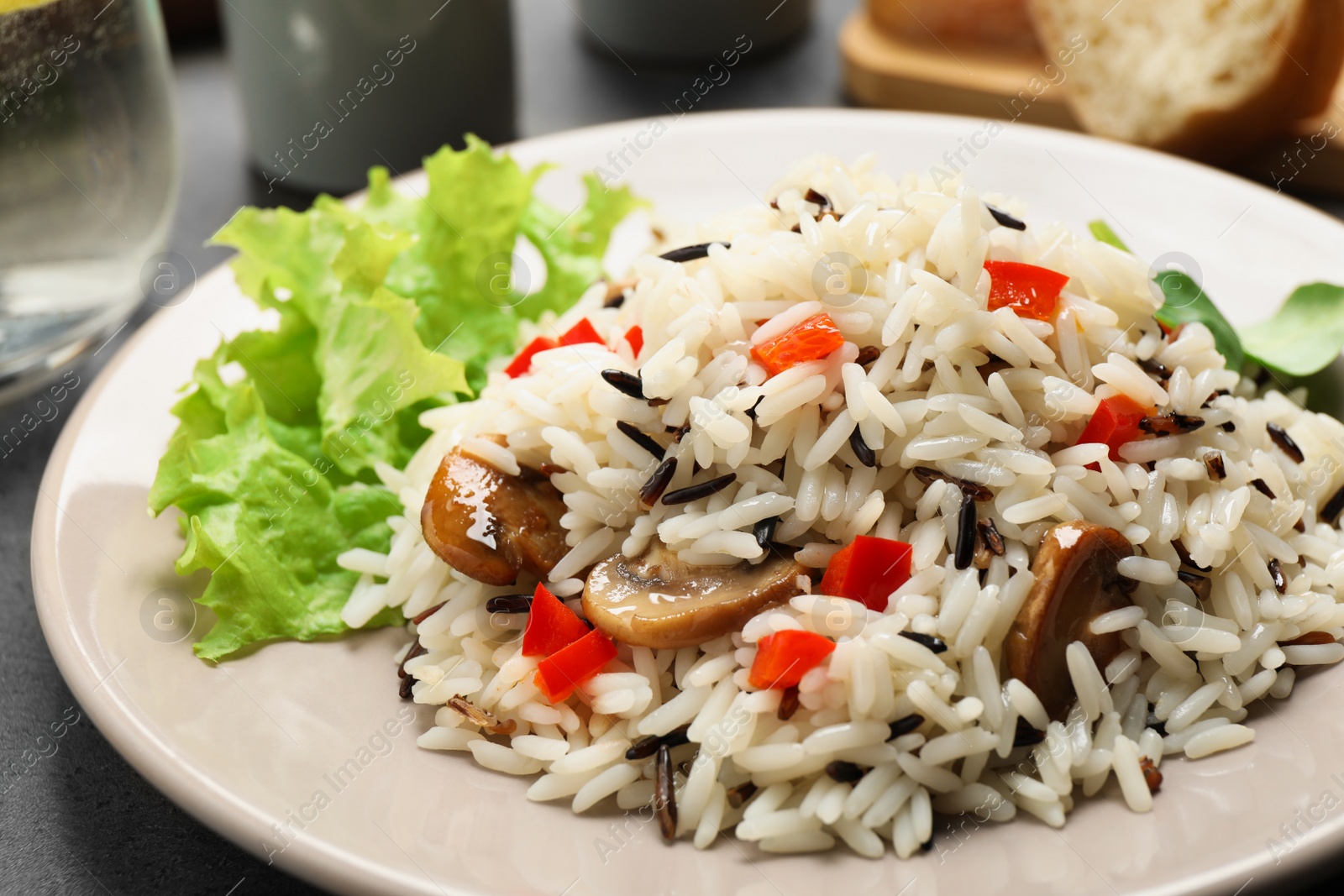 Photo of Delicious rice pilaf with mushrooms on plate, closeup