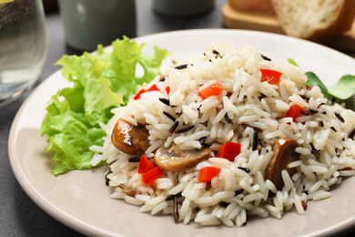 Photo of Delicious rice pilaf with mushrooms on plate, closeup