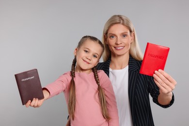 Immigration. Happy woman and her daughter with passports on gray background