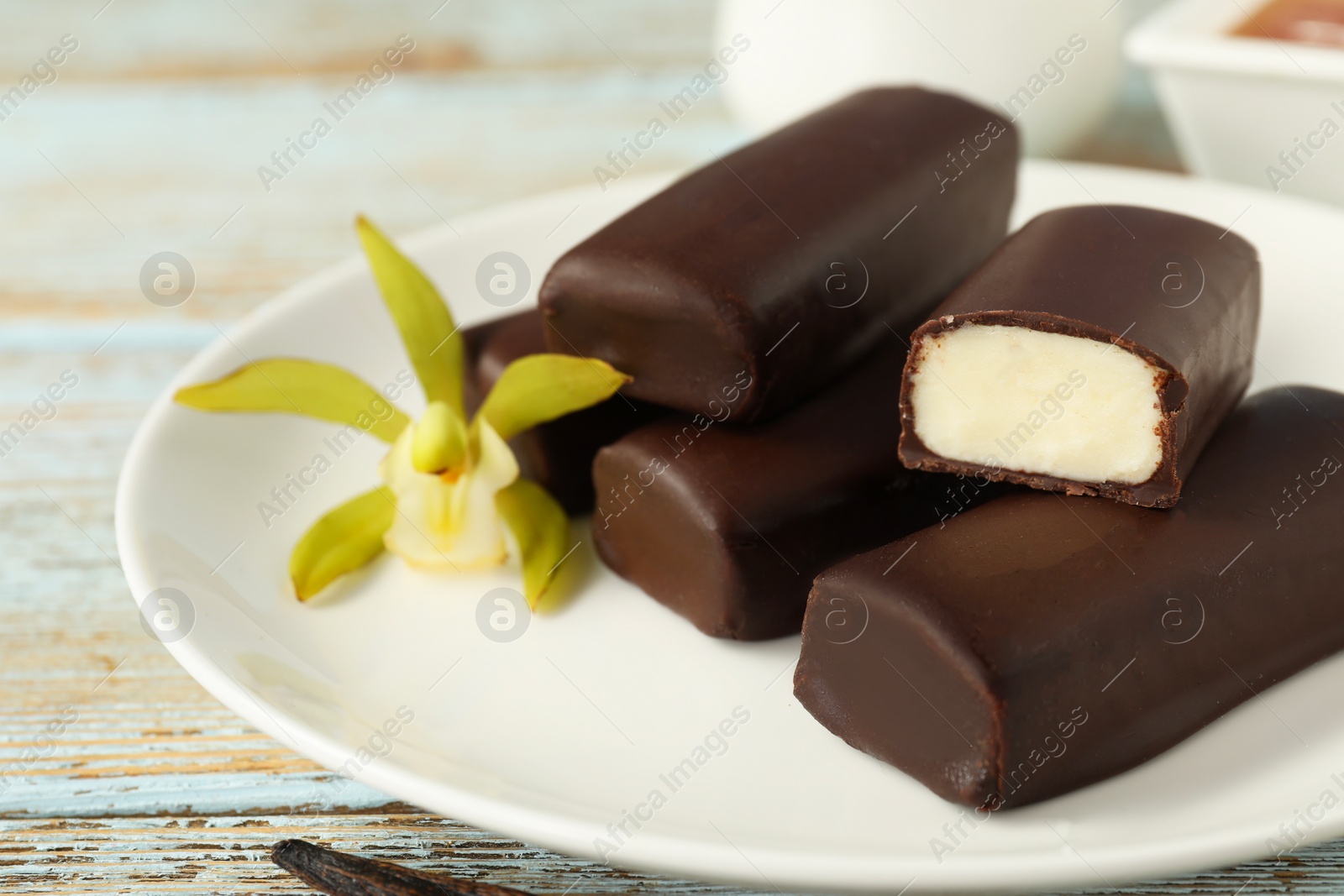 Photo of Glazed vanilla curd cheese bars served on wooden table, closeup