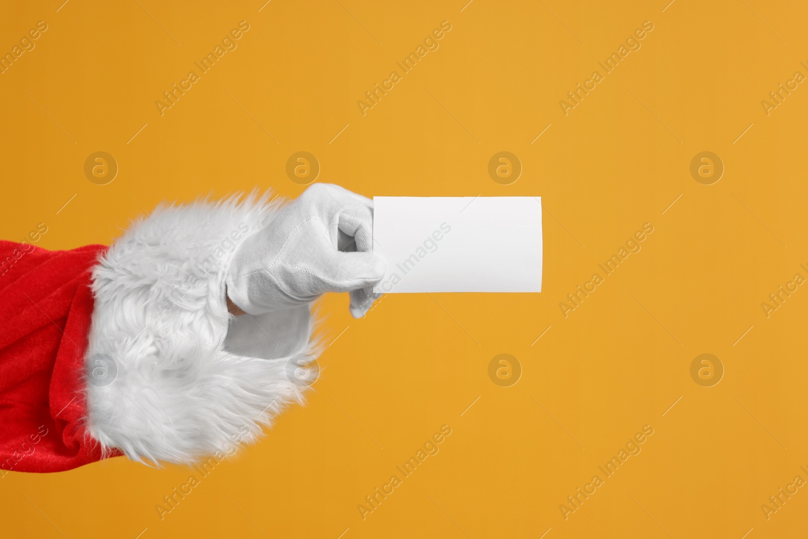 Photo of Merry Christmas. Santa Claus holding blank card on orange background, closeup. Space for text