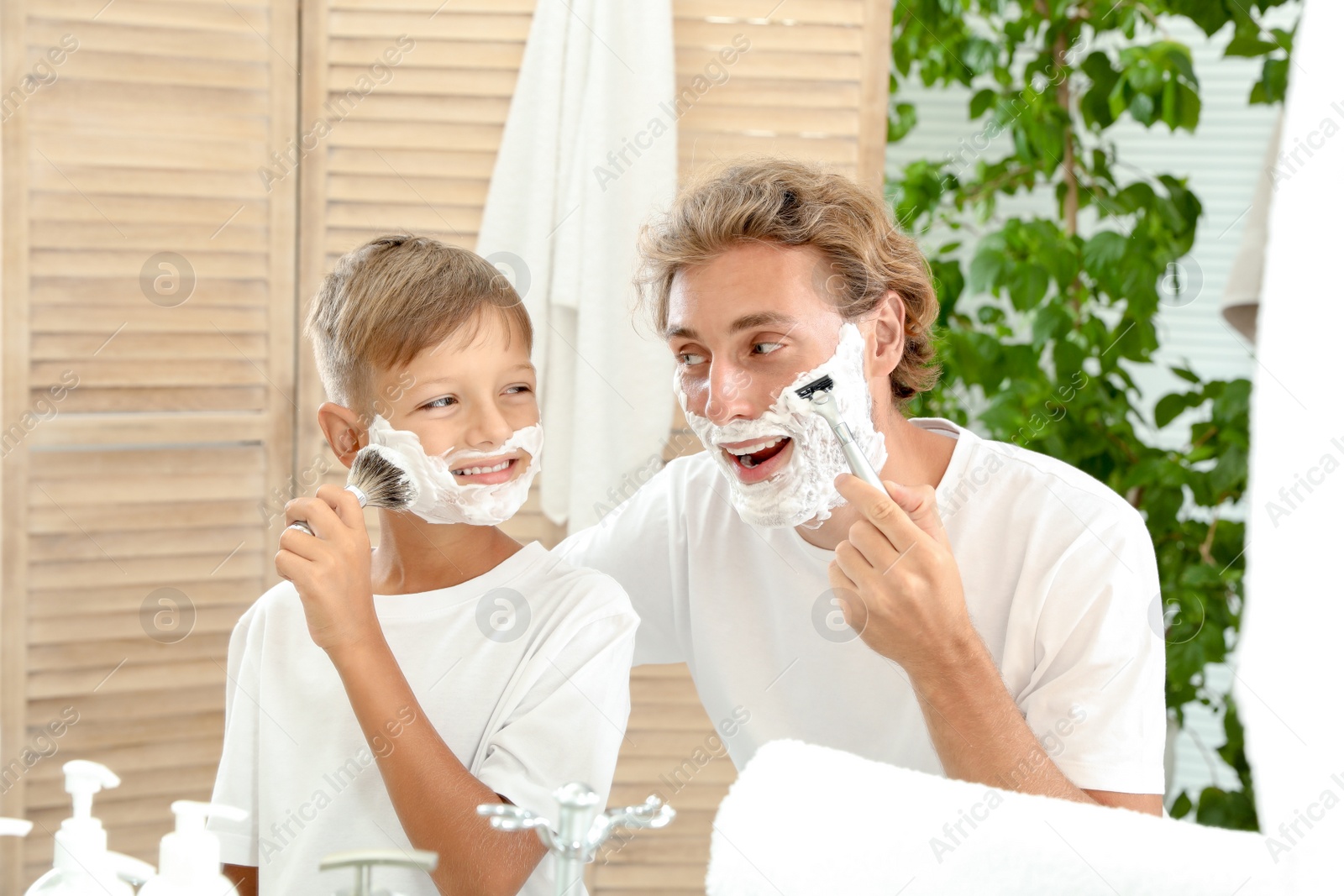 Photo of Father and son shaving together in bathroom