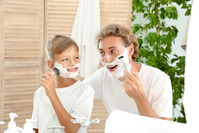 Father and son shaving together in bathroom