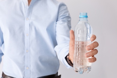 Man holding bottle of pure water on white background, closeup