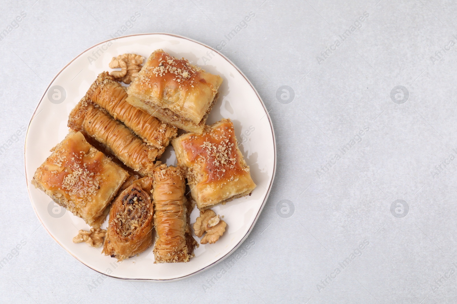 Photo of Eastern sweets. Pieces of tasty baklava on white table, top view. Space for text