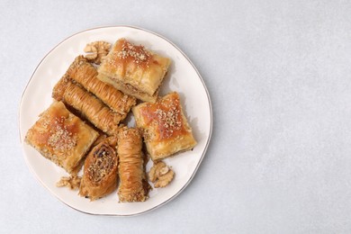 Photo of Eastern sweets. Pieces of tasty baklava on white table, top view. Space for text