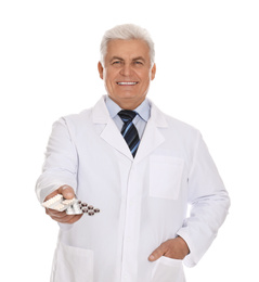 Senior pharmacist with pills on white background