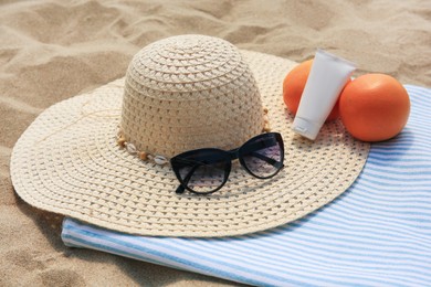 Photo of Beach accessories and oranges on sand, closeup