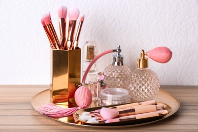 Photo of Makeup brushes and perfumes on wooden dressing table