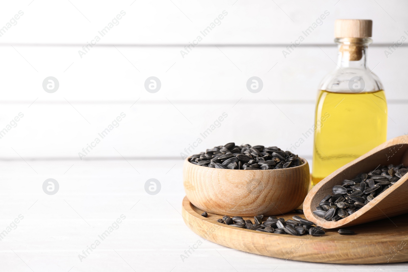 Photo of Sunflower seeds and oil on white table. Space for text