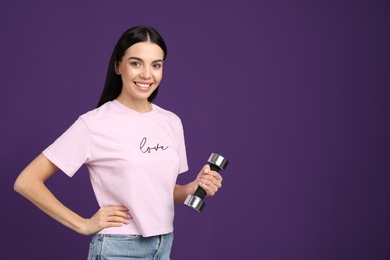 Photo of Woman with dumbbell as symbol of girl power on purple background, space for text. 8 March concept