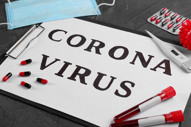 Photo of Paper with words CORONA VIRUS, blood samples and medicines on grey stone background, closeup