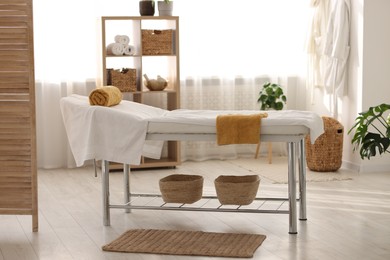 Comfortable massage table with clean towels in spa center