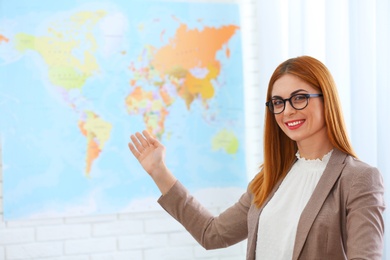 Beautiful consultant showing map in travel agency. Space for text