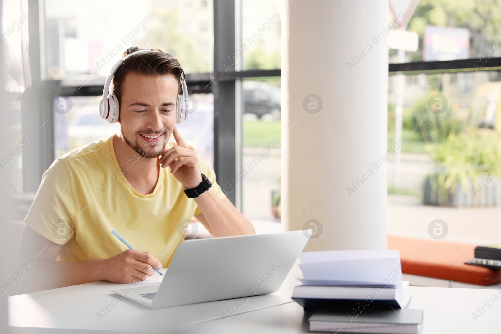 Photo of Young man studying at table in modern library