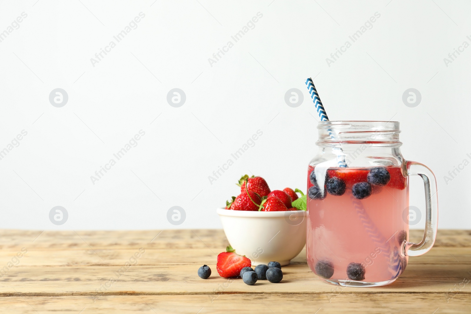 Photo of Natural lemonade with berries in mason jar on wooden table