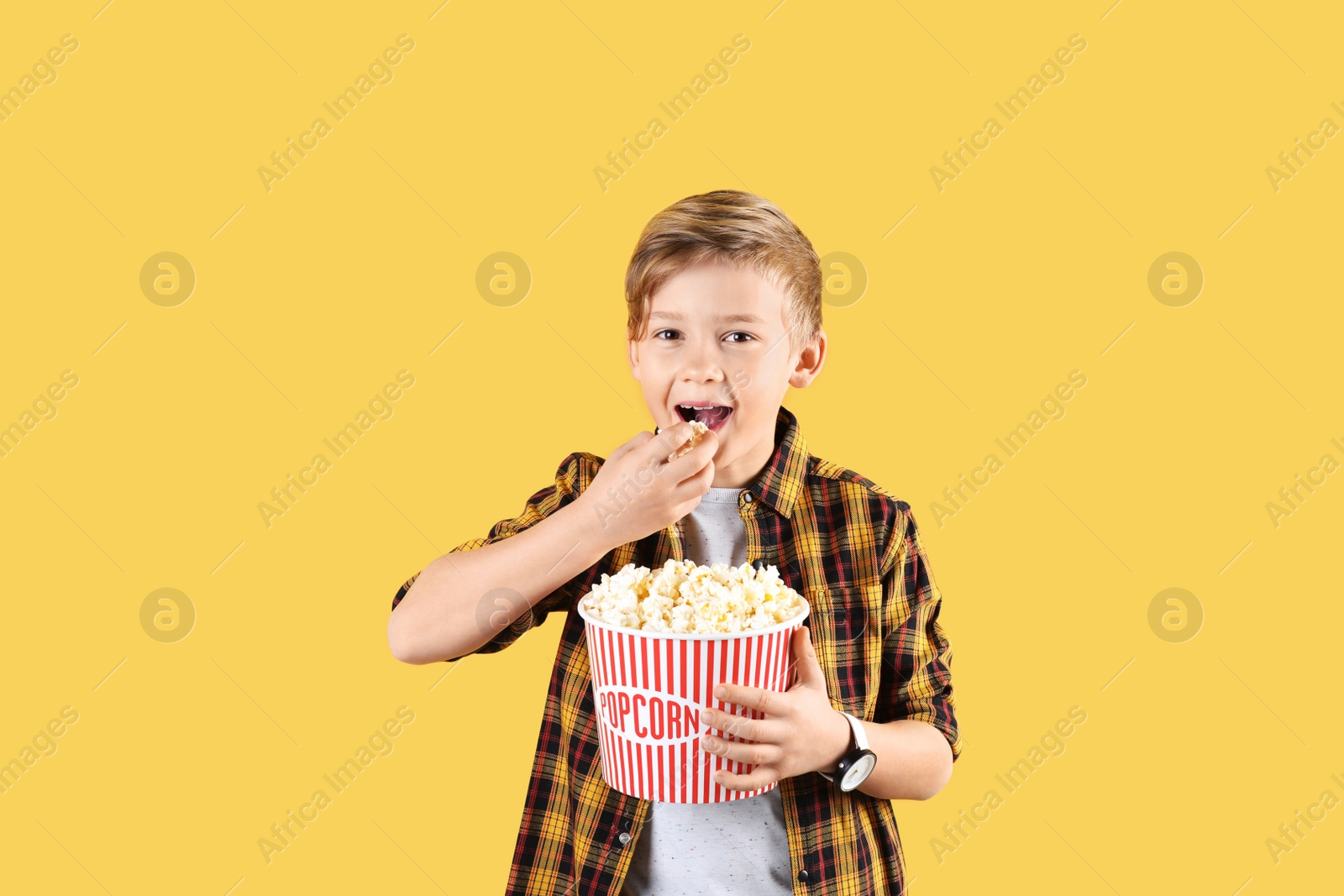 Photo of Cute boy with popcorn bucket on color background