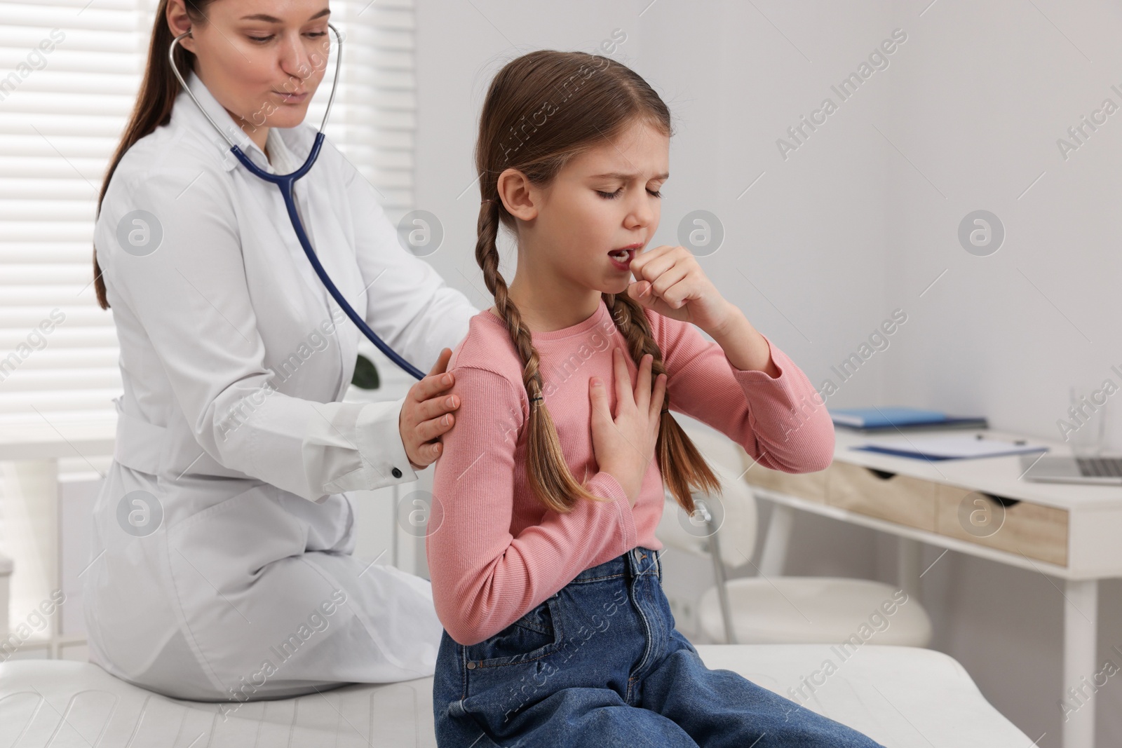 Photo of Doctor examining coughing girl in hospital. Cold symptoms