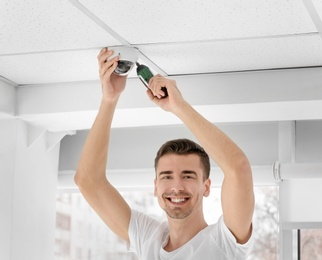 Technician installing CCTV camera on ceiling indoors