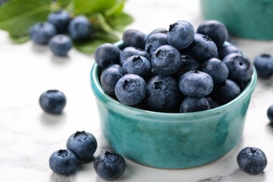 Photo of Tasty fresh blueberries on white marble table, closeup